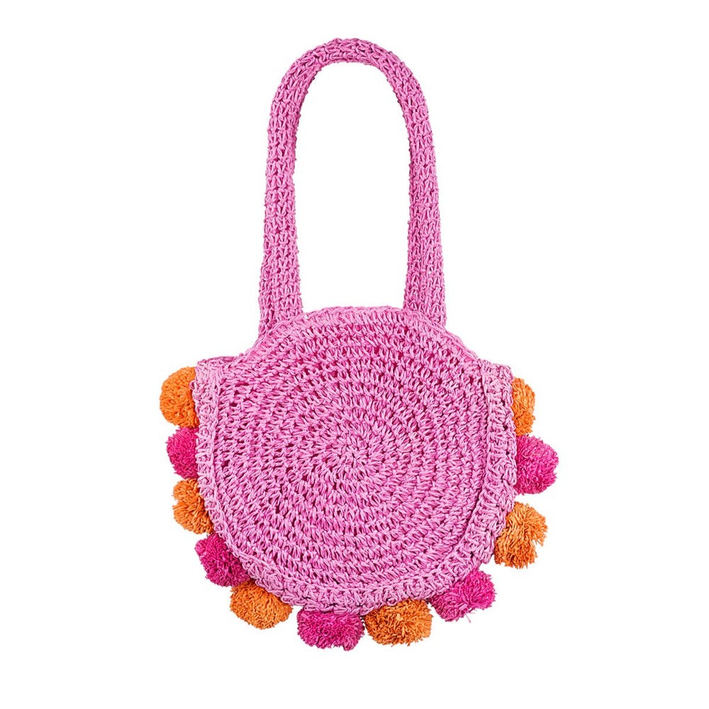 Round woven Pom Pom Beach Bag in Pink Orchid featuring playful pom pom details