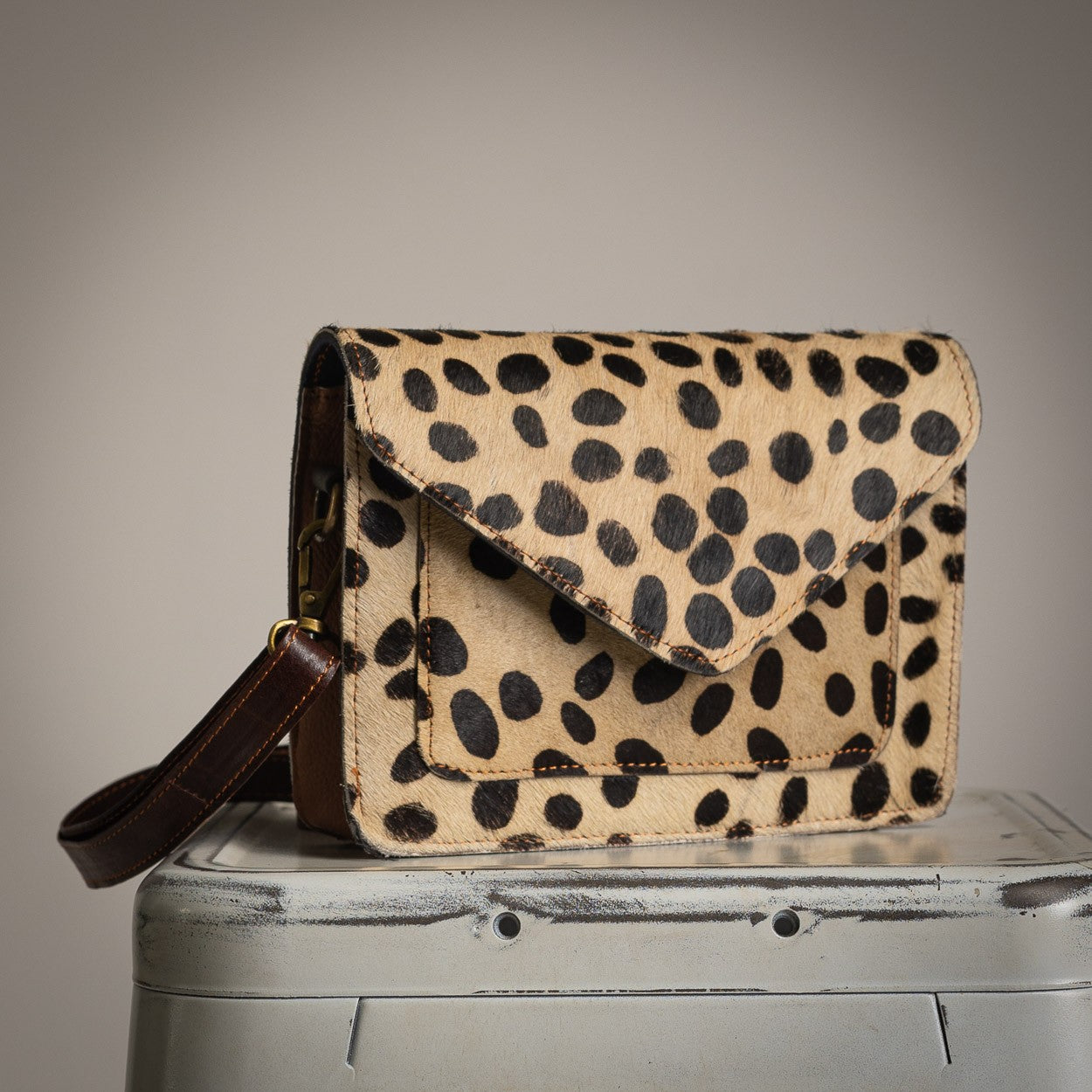 Spotted leather crossbody bag with flap closure and structured design