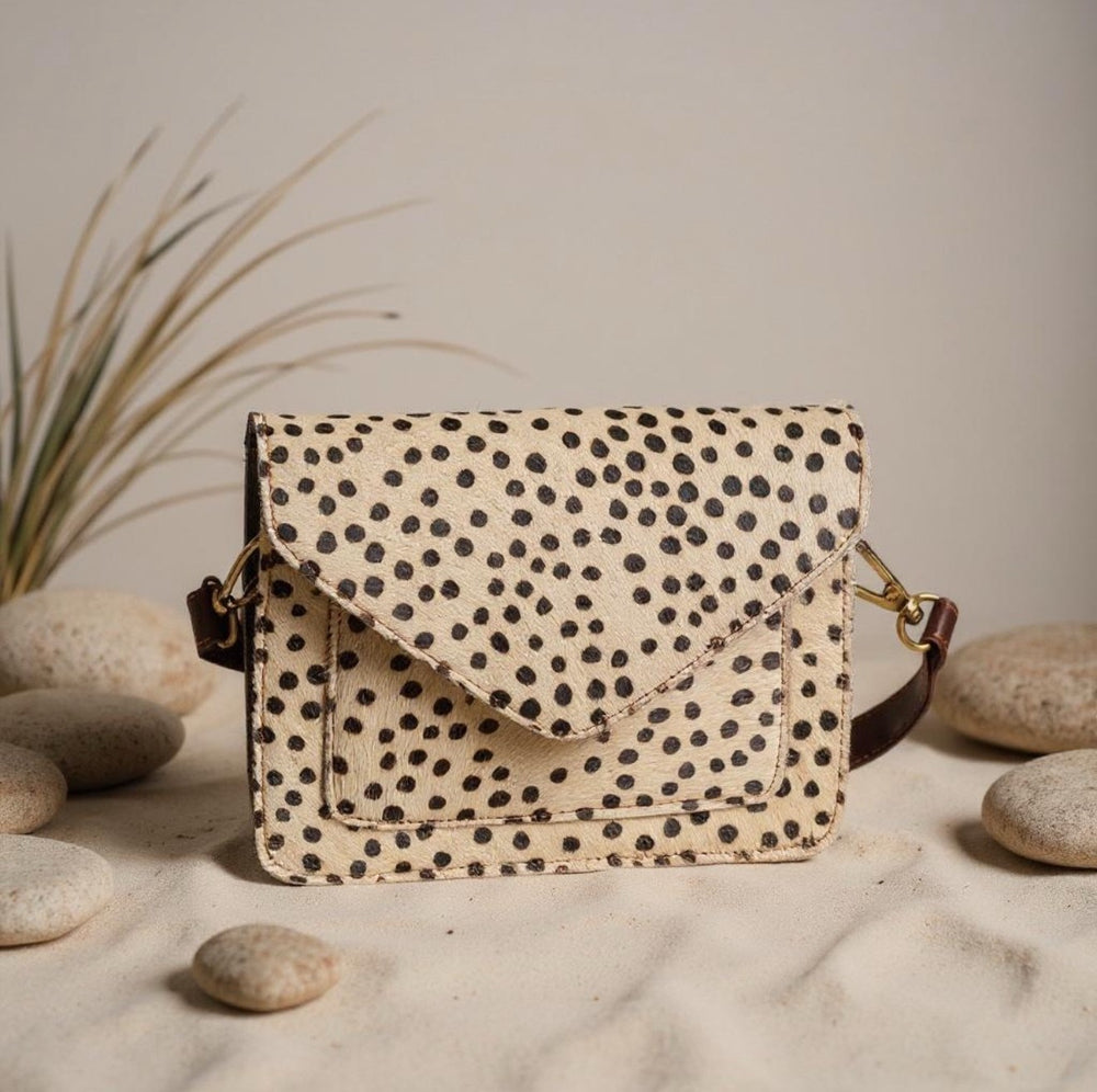 Spotted leather crossbody bag with natural stones background and flap closure