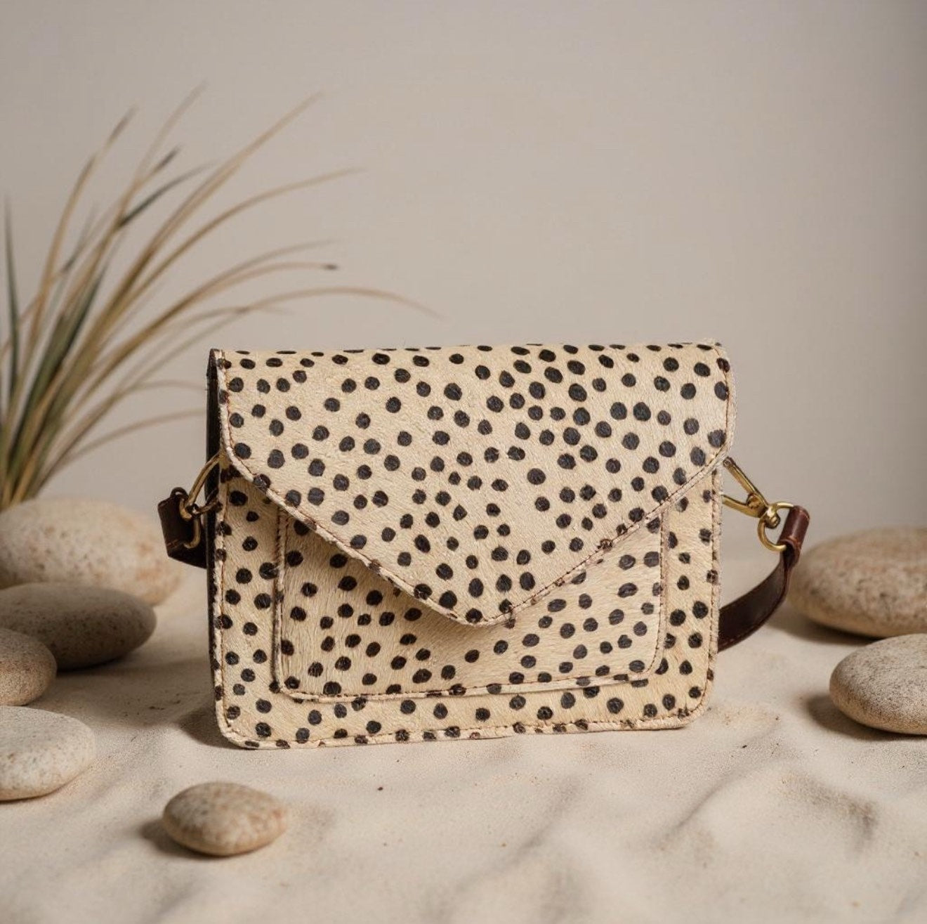 Spotted leather crossbody bag with natural stones background and flap closure