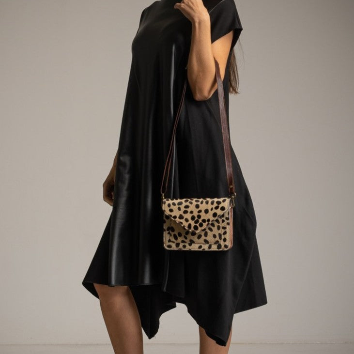 Spotted leather crossbody bag worn with black dress