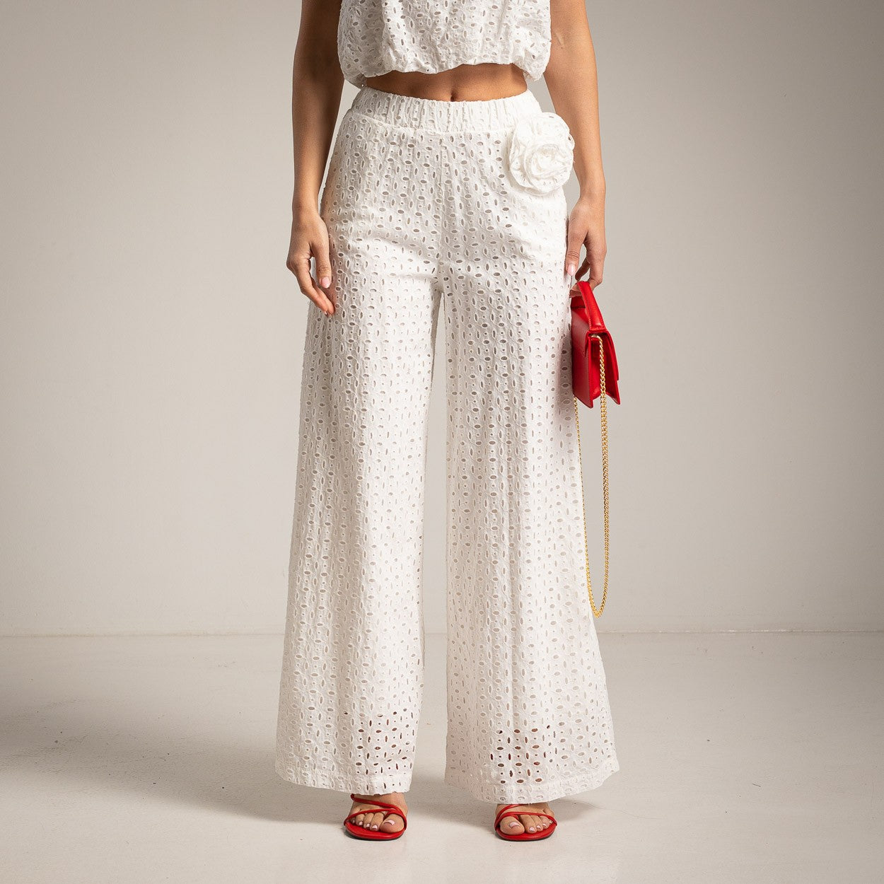 Close-up of white broderie anglaise co-ord set featuring sleeveless top and elastic waist wide leg pants