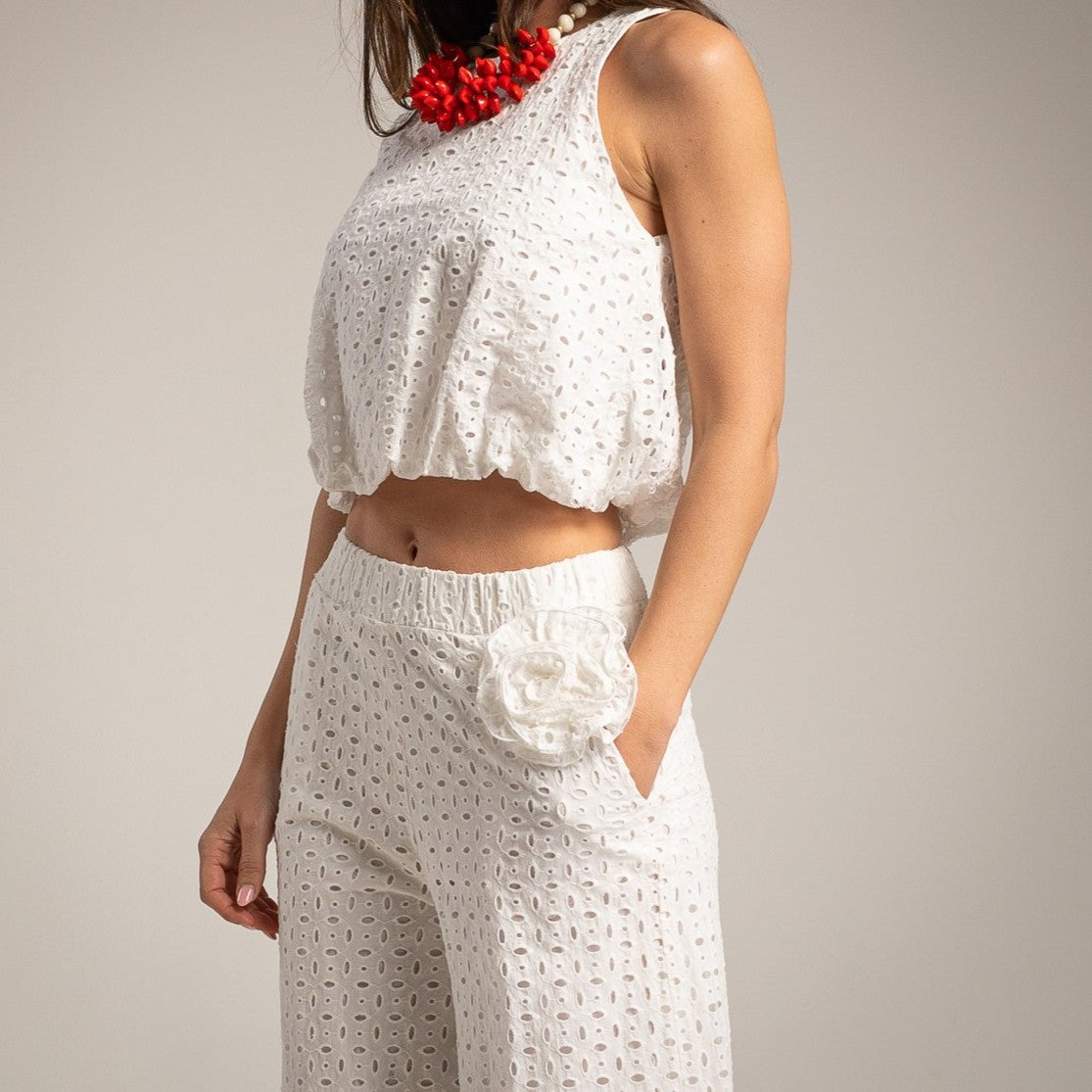 White broderie anglaise sleeveless top and wide leg pants set with floral waist detail and red accessories